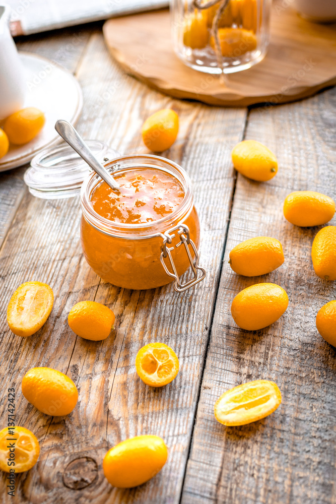 kumquat on plate and jam in jar at wooden table