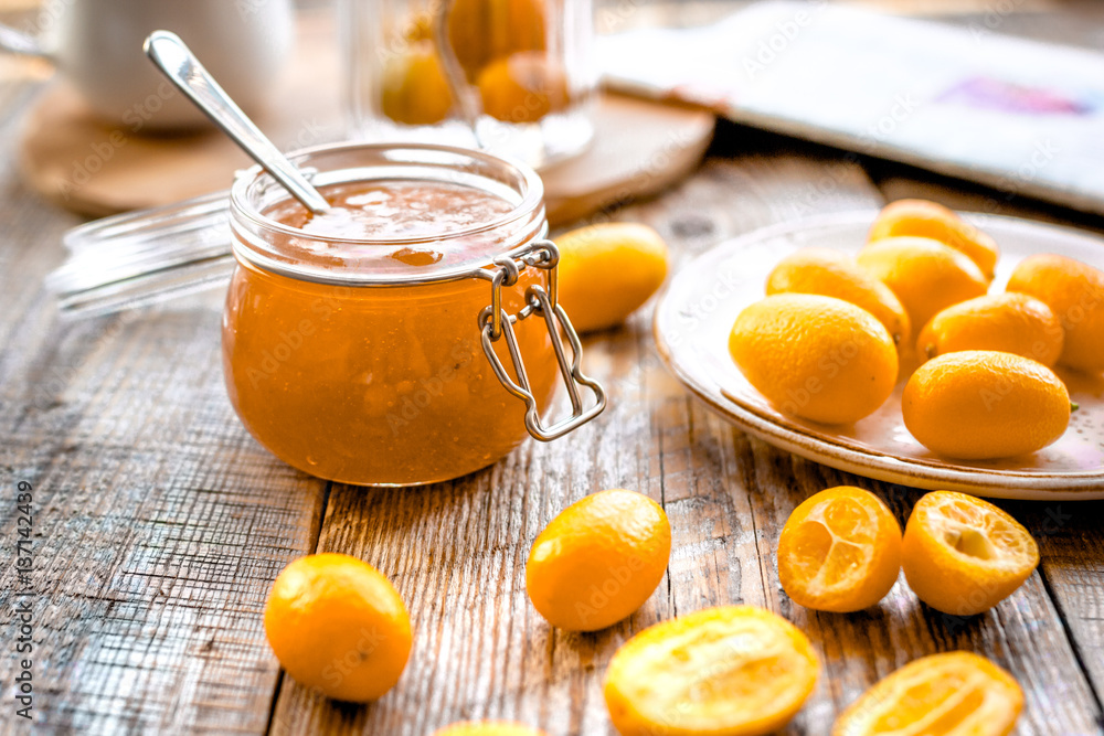 kumquat on plate and jam in jar at wooden table