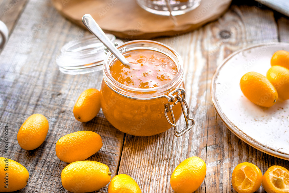 kumquat on plate and jam in jar at wooden table