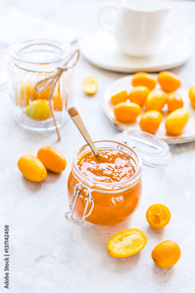 kumquat on plate and jam in jar at gray background