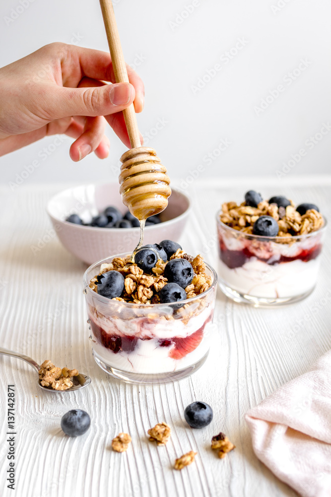 Cooking breakfast with granola and berries on white kitchen background