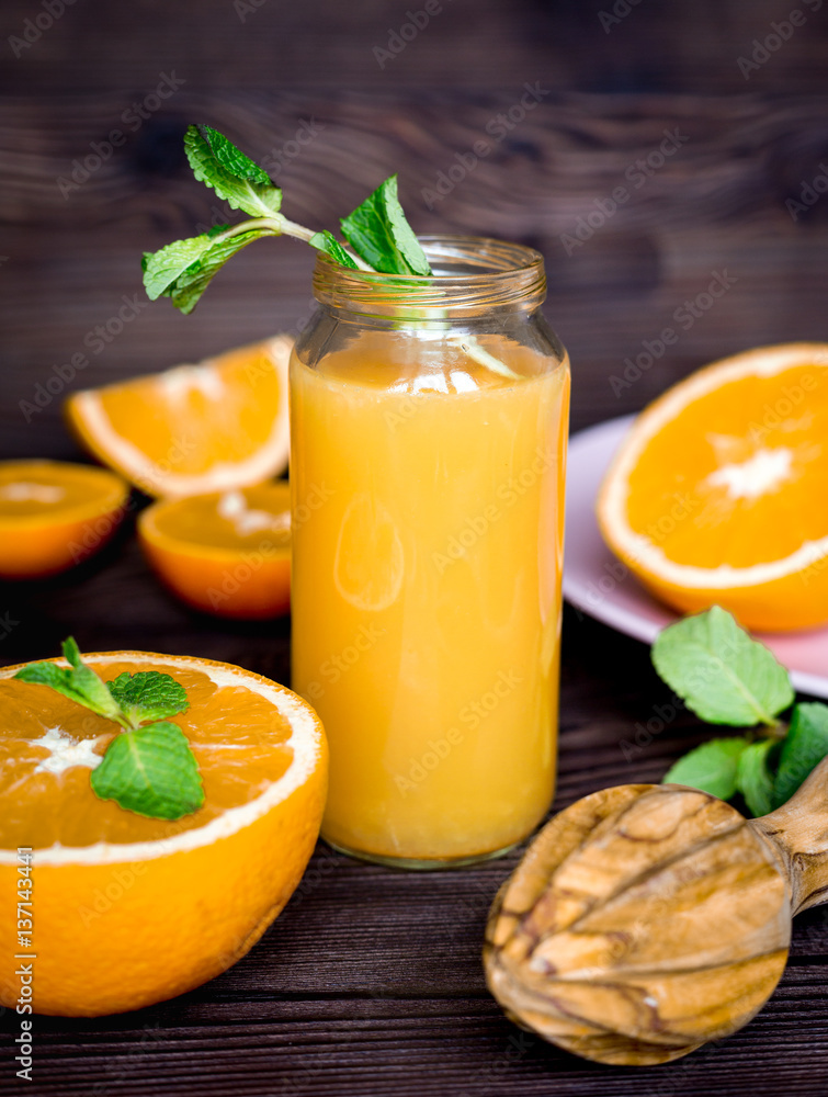 healthy orange cocktail with mint leaves in bottle on kitchen background