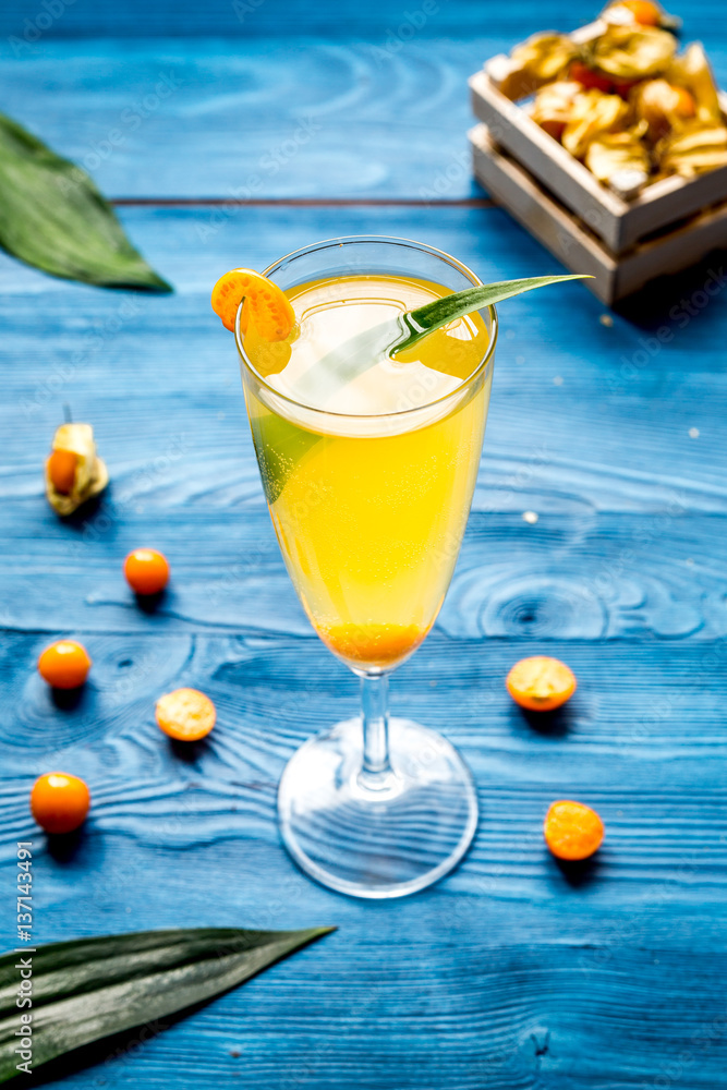 cocktail with physalis in glass on wooden background