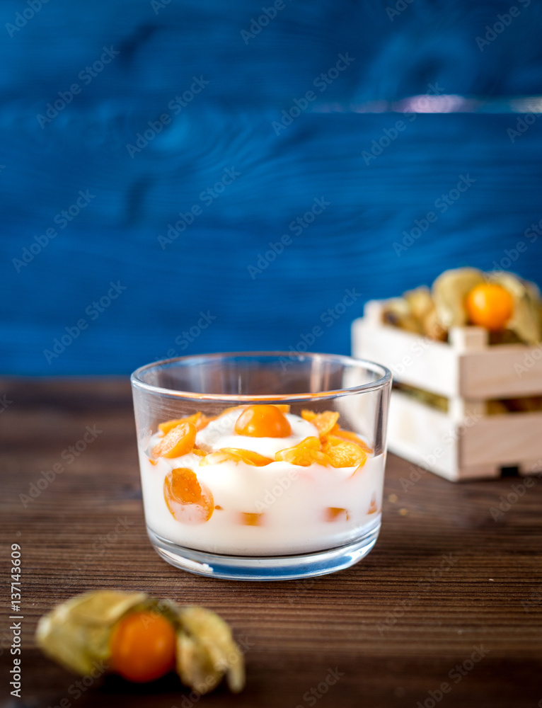 yogurt with physalis on wooden background