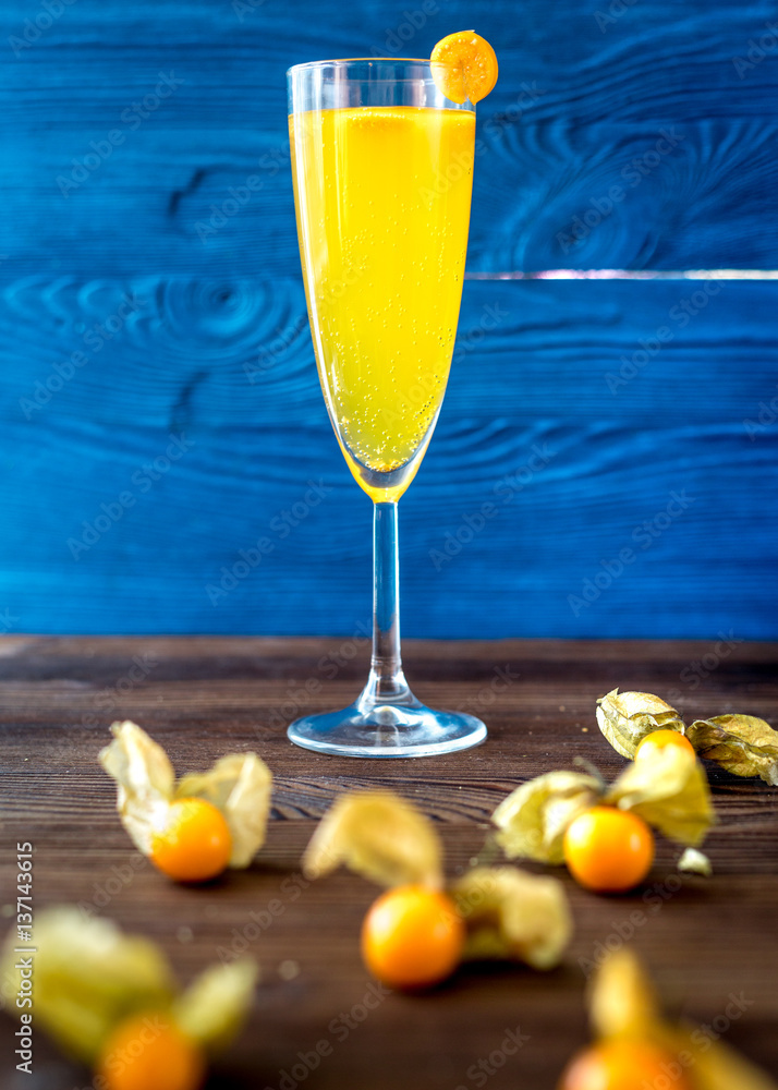 cocktail with physalis in glass on wooden background