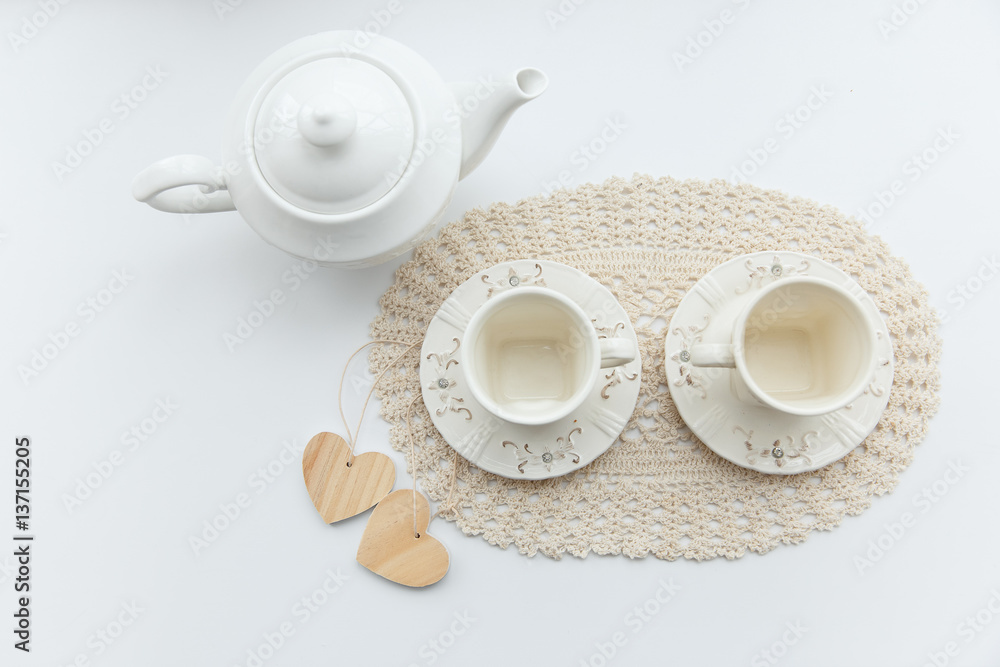 Tea for two. Two white cups of tea with two hearts and kettle.