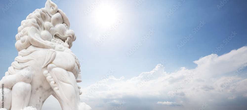 white stone lion sculpture in blue sunny sky