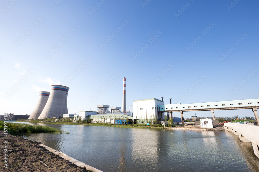 modern power plant near river in blue sky