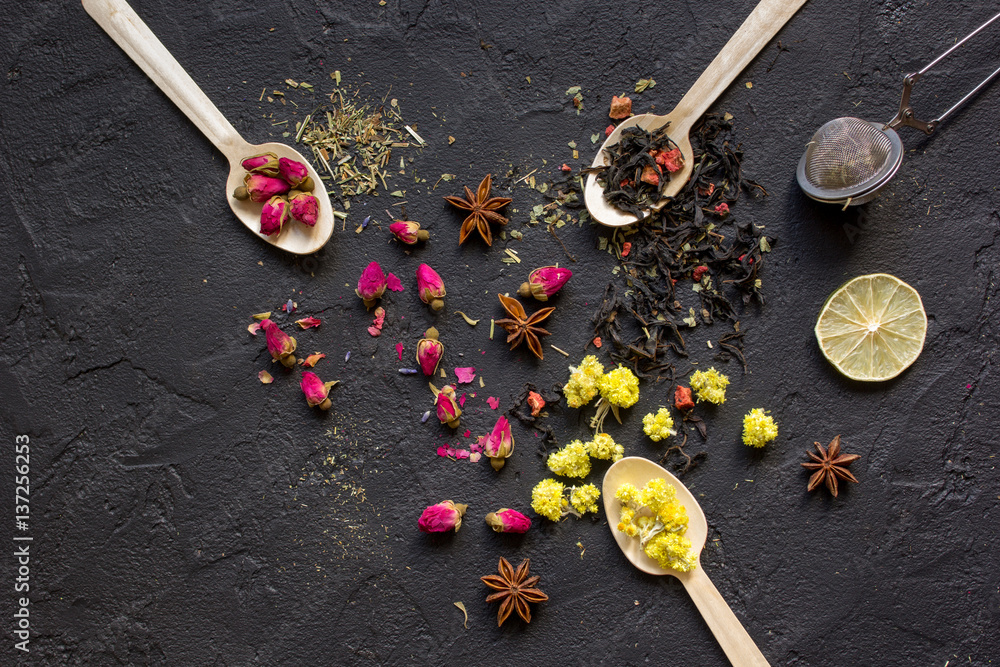 Spoons with herbs on dark background top view