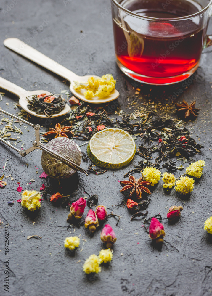 Teacup and herbs on dark stone background