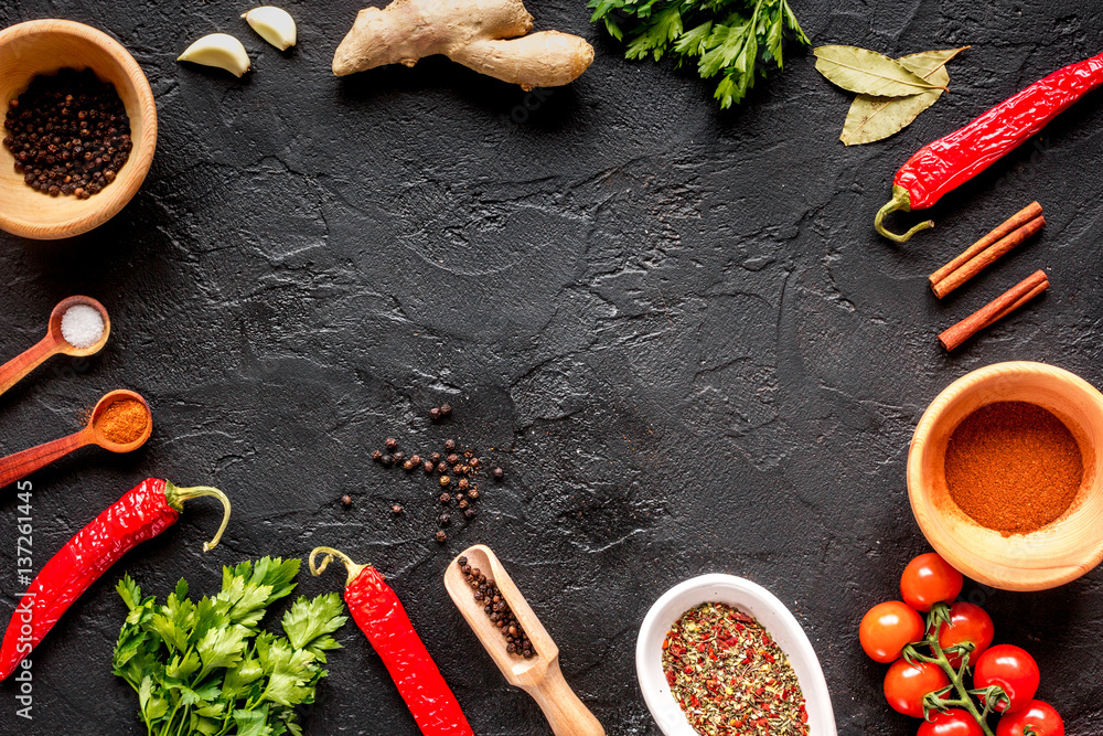 spices in wooden spoon on dark background top view