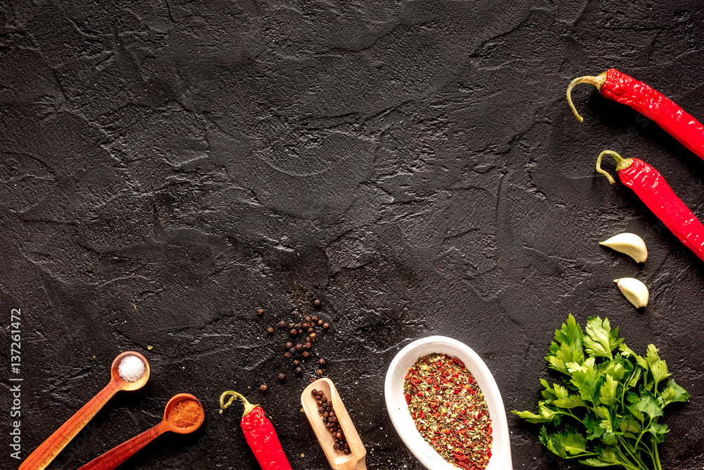 spices in wooden spoon on dark background top view