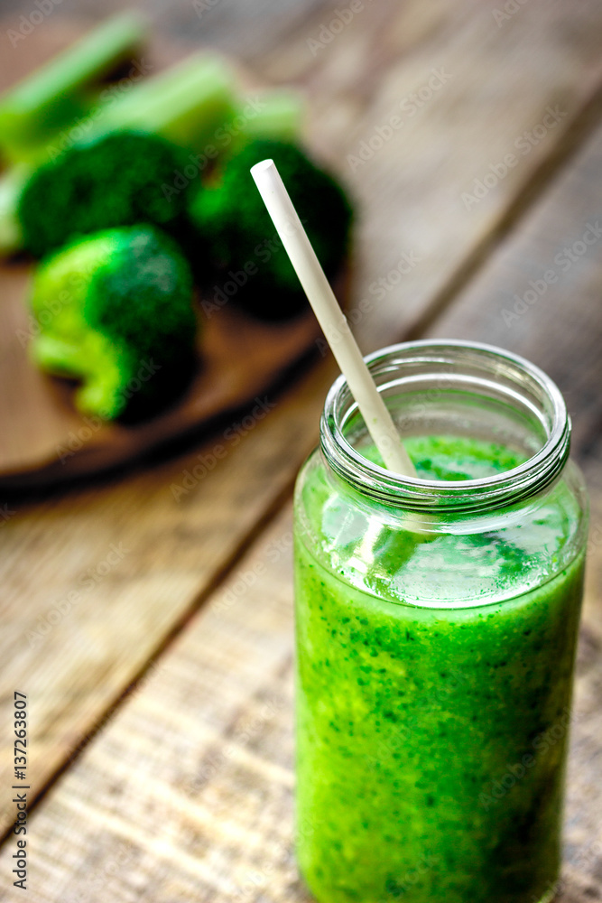 Green vegetable smoothie in glass at wooden background