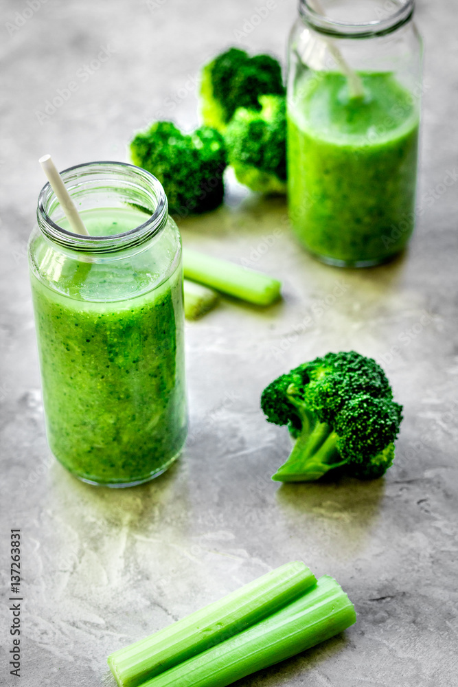 Green vegetable smoothie in glass at gray background