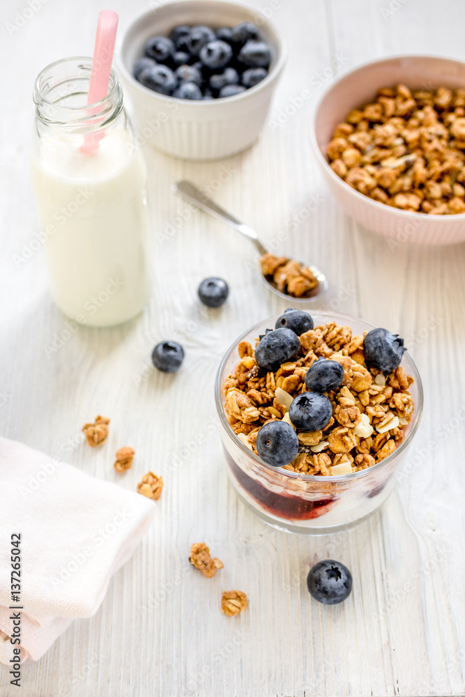 Fitness breakfast with granola, milk and berries on white background