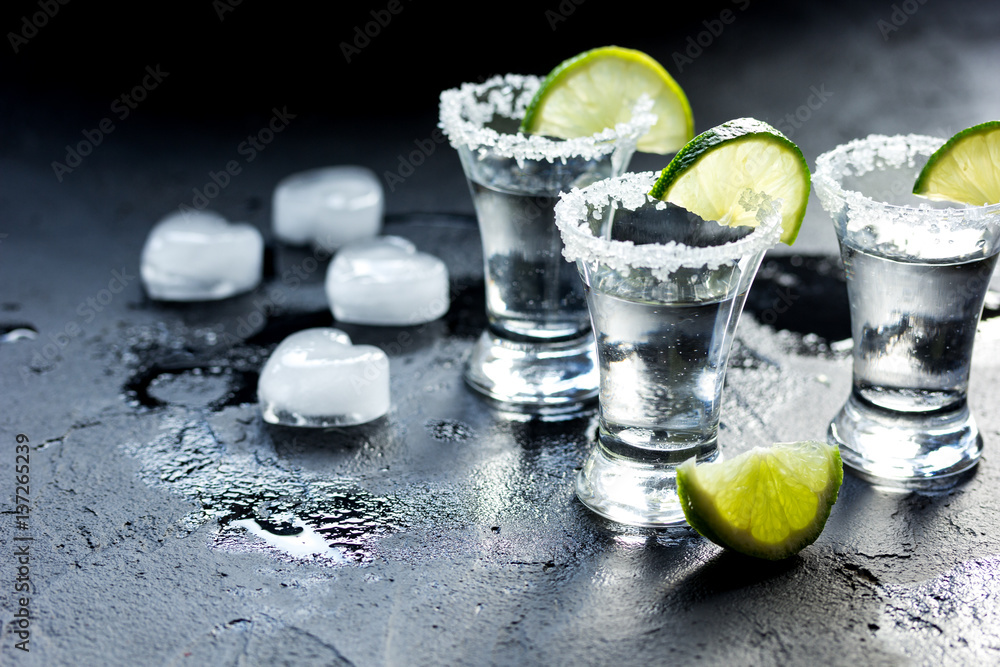 Tequila shot with salt and ice on dark background