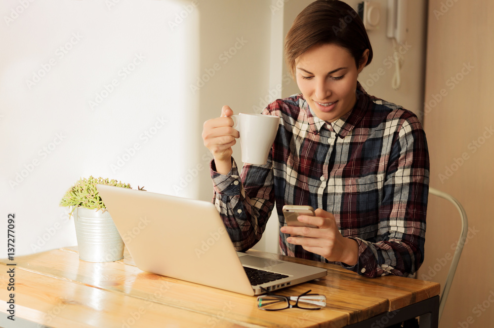 Portrait of a happy girl texting and holding cup of coffee