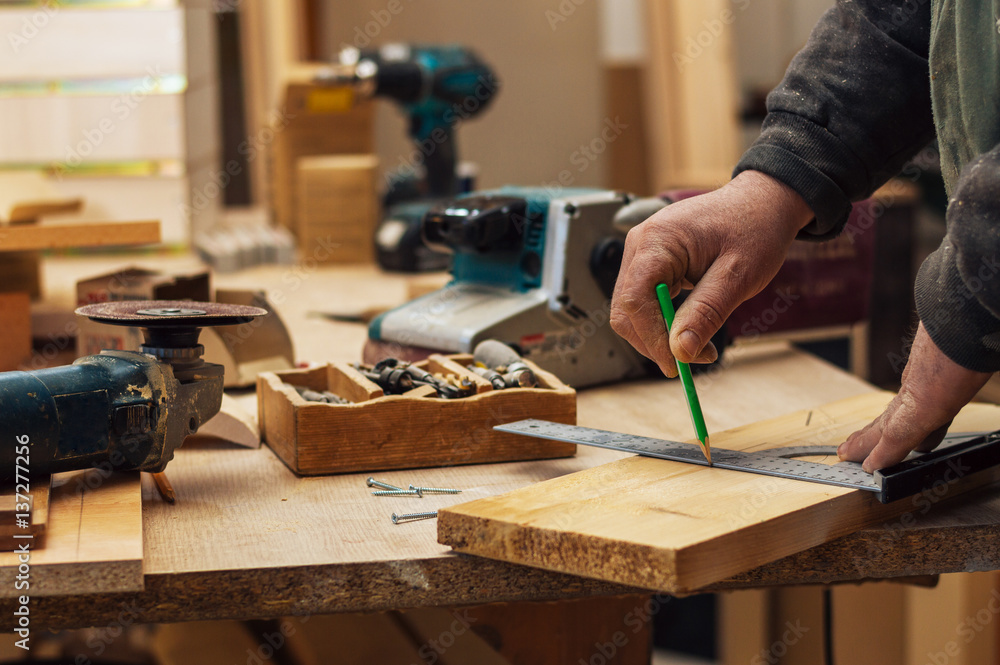 Hand of a carpenter taking measurement of a wooden plank, wood working