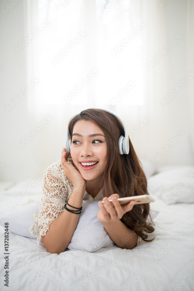 Woman Relaxing in bed and listening to music, relaxing in her living room