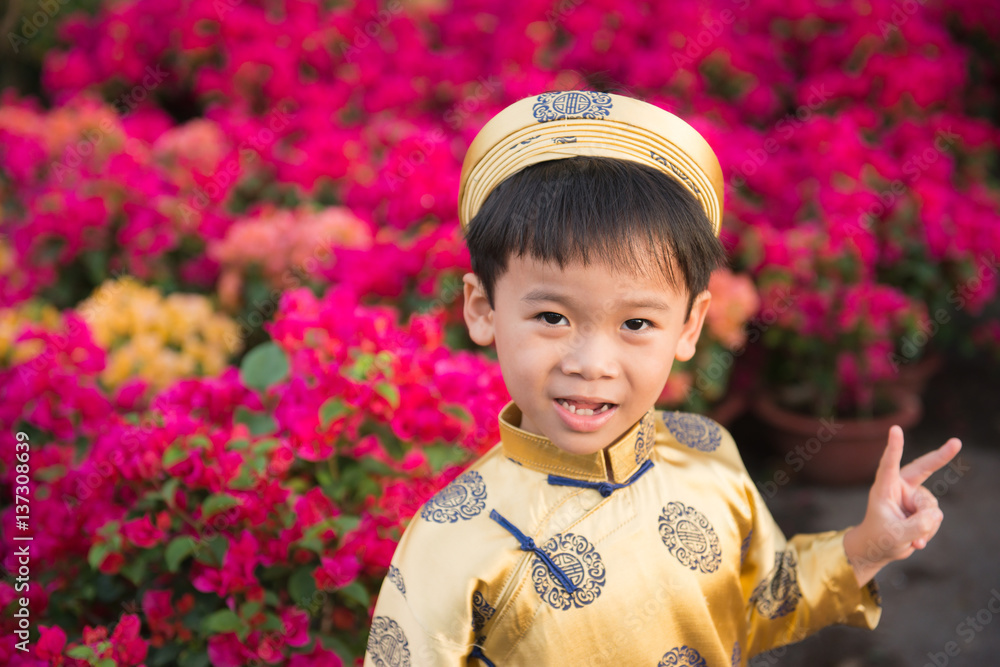 Happy kid having fun with traditional dress (ao dai) in Ochna Integerrima (Hoa Mai) garden. Hoa Mai 