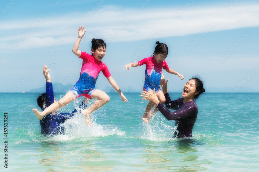 Happy Asian family playing in the ocean and splashing water in Phuket, Thailand. Asian family touris