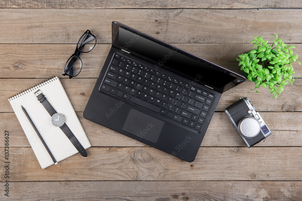 Workplace from above - laptop, notepad, glasses and camera on the wooden desk