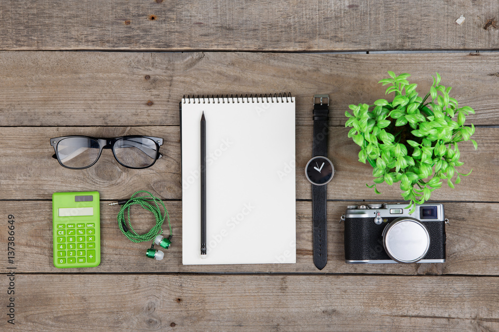 Notepad, glasses and camera on the wooden desk