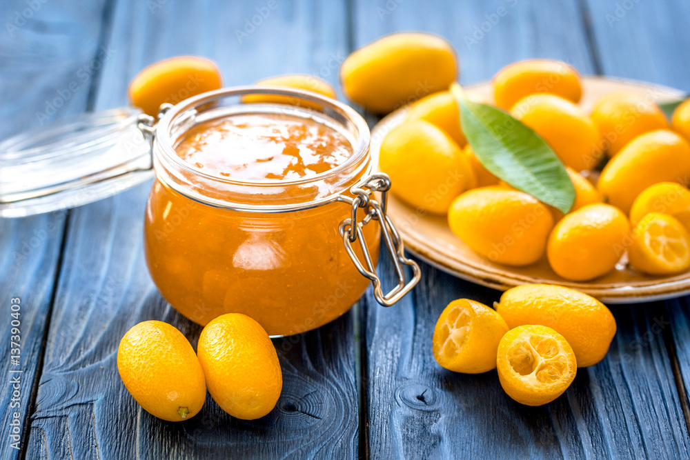 kumquat on plate and jam in jar at wooden table