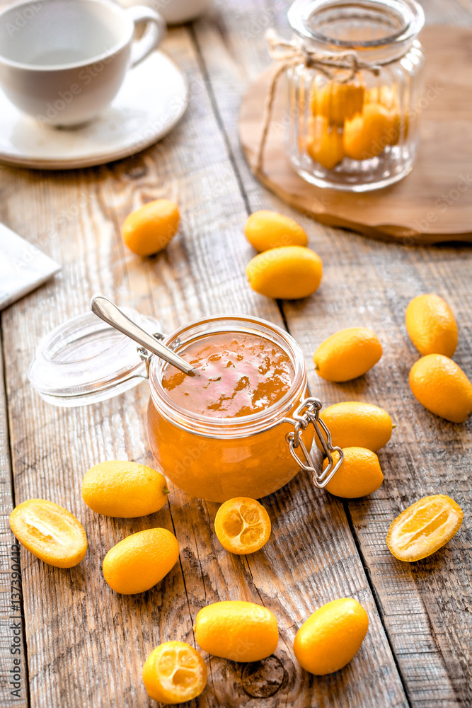 kumquat on plate and jam in jar at wooden table