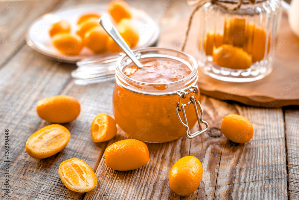 kumquat on plate and jam in jar at wooden table