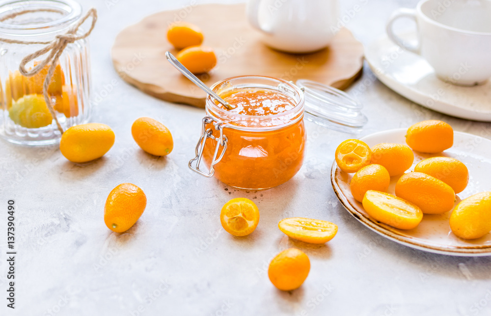 kumquat on plate and jam in jar at gray background