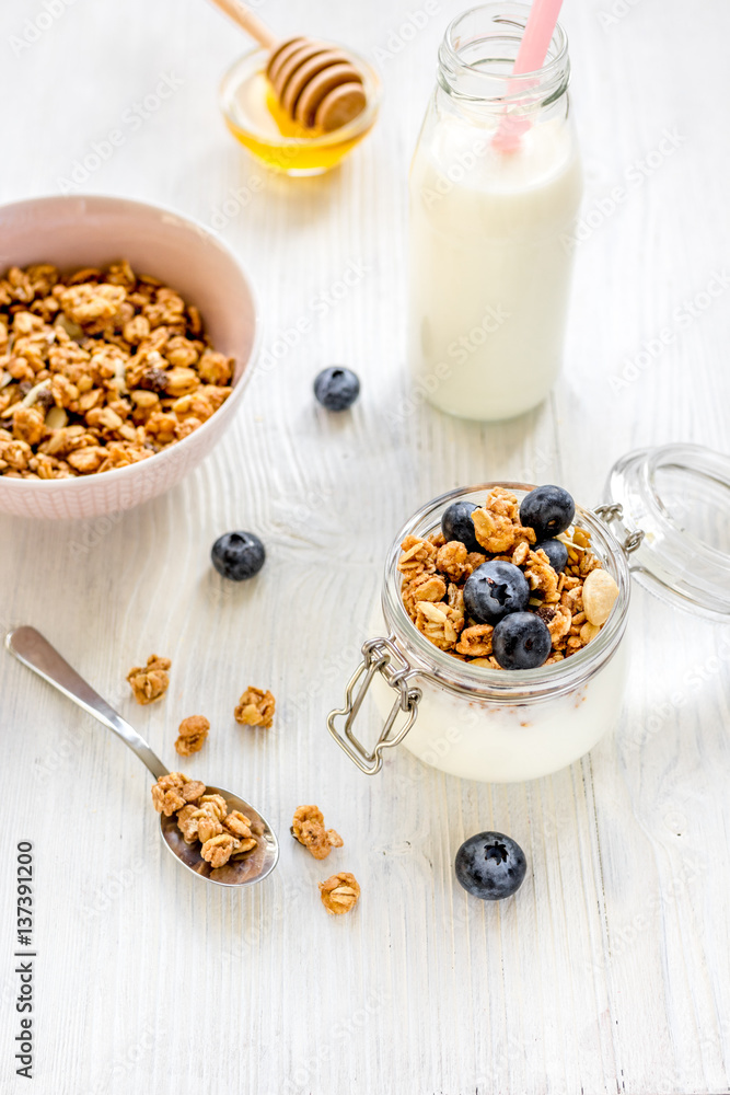 Homemade granola with blueberries in jar on white kitchen background