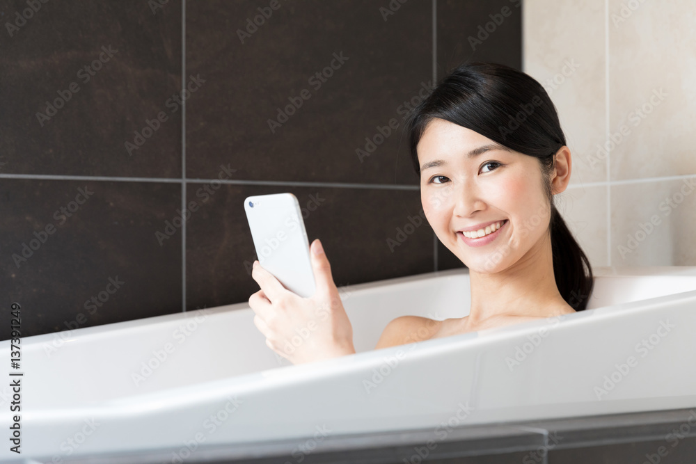 attractive asian woman relaxing in bathtub