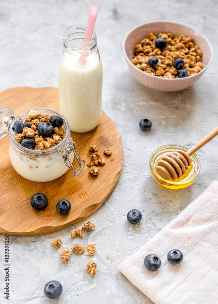 Morning granola with yogurt, honey and berries on white table