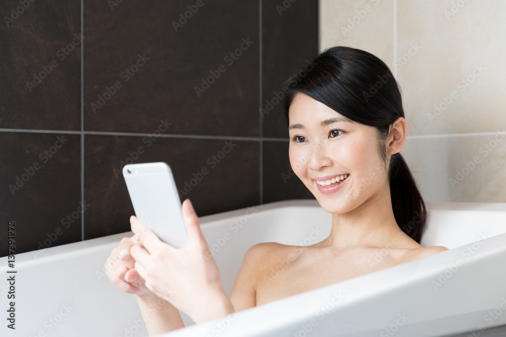 attractive asian woman relaxing in bathtub