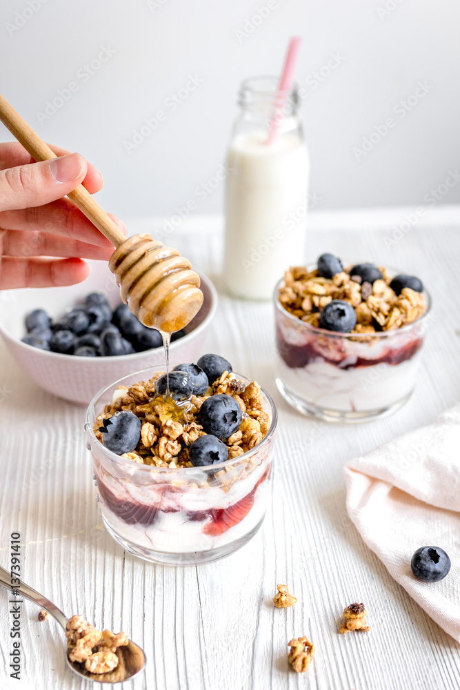 Cooking breakfast with granola and berries on white kitchen background