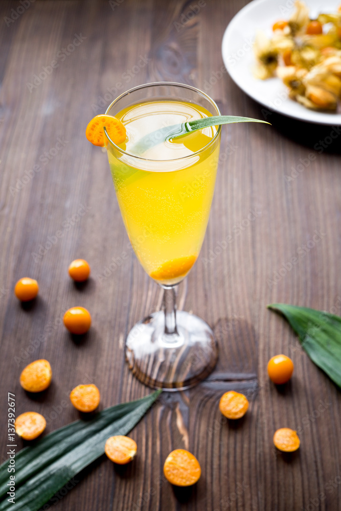 cocktail with physalis in glass on wooden background