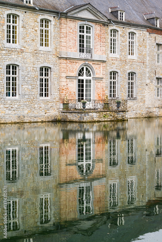 Magnifique façade dun château à dominante orange beige. Reflet sur leau du lac. Balcon en fer forg