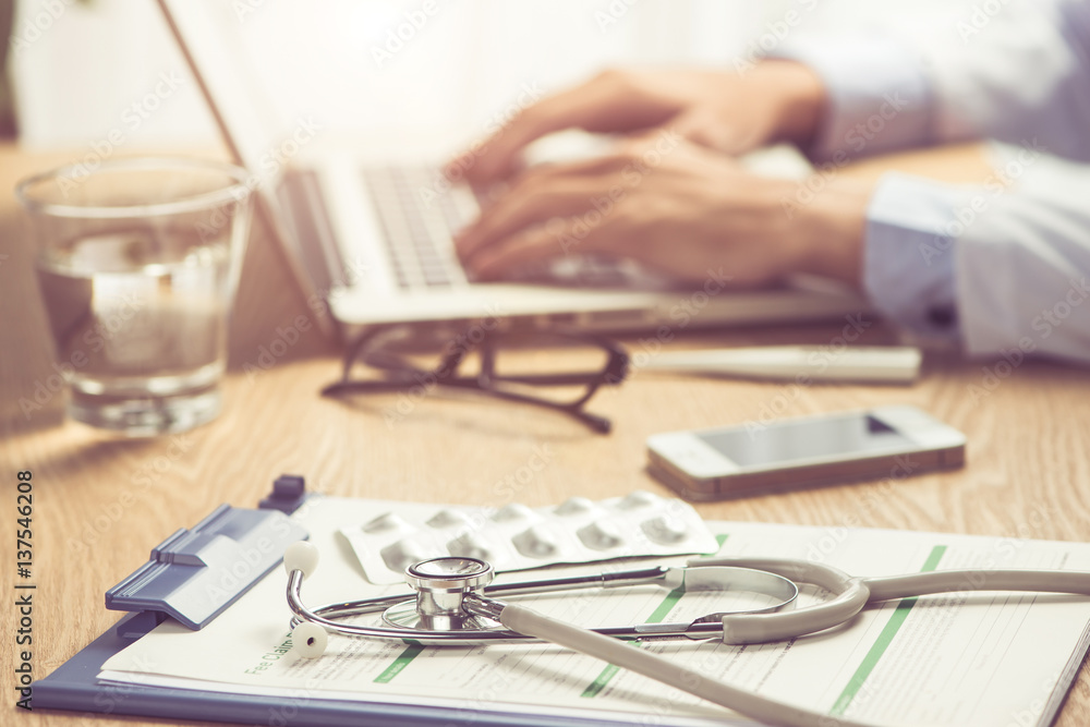 Male doctor working at wooden desk in clinic