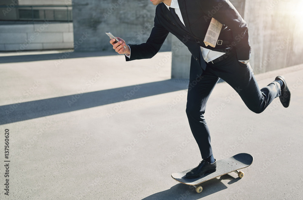 Businessman on a skateboard checking his phone