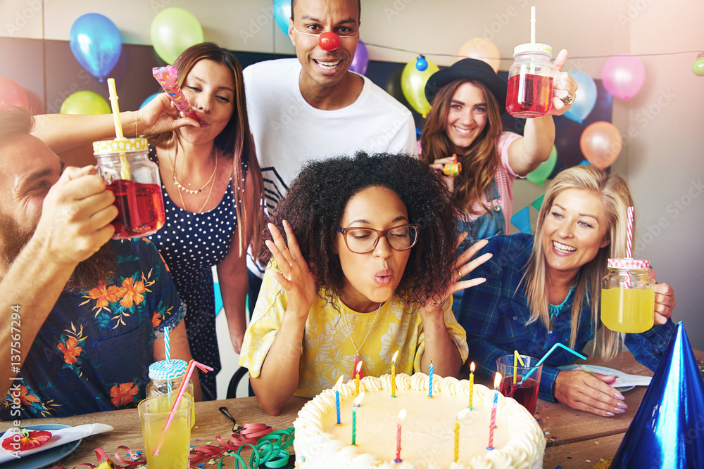 Woman with eyeglasses blowing on cake candles