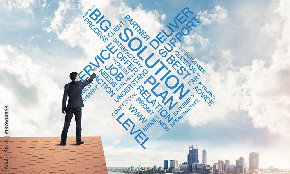 Young businessman standing on house roof and writing leadership 