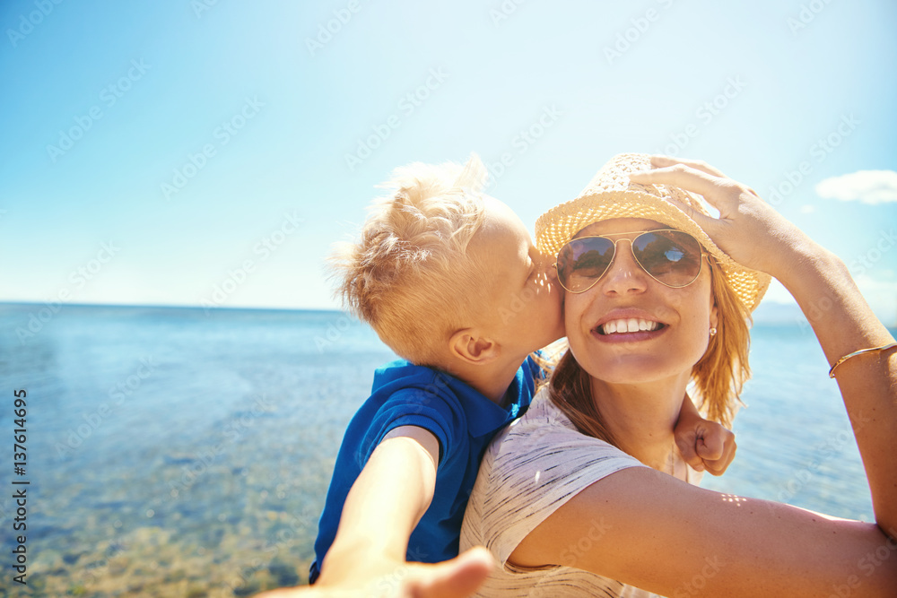 Woman holding boy on back kissing her