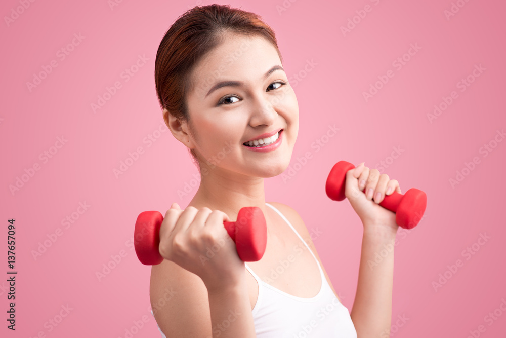 Woman Lifting Weights. Fitness woman lifting weights smiling happy on pink background.