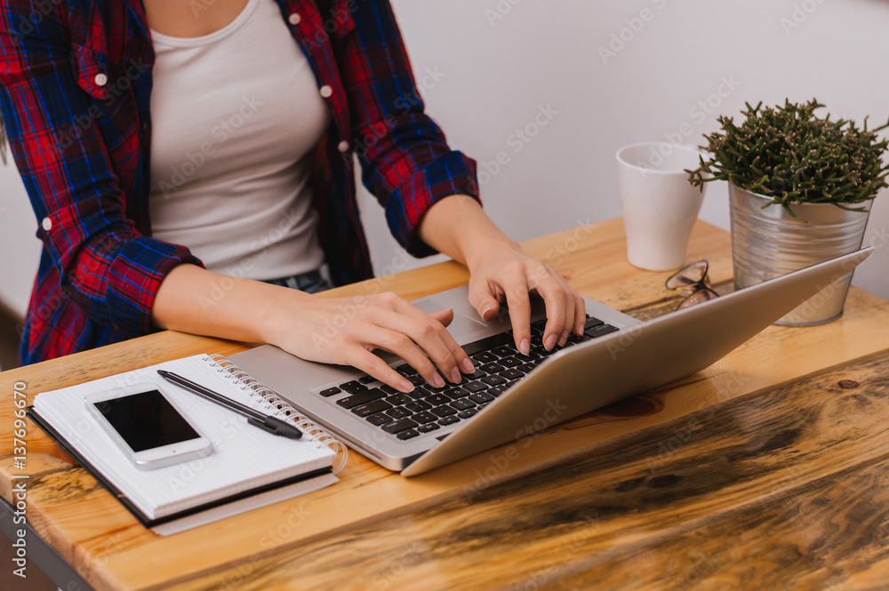 Closeup of female hands typing on laptop keyboard in modern office