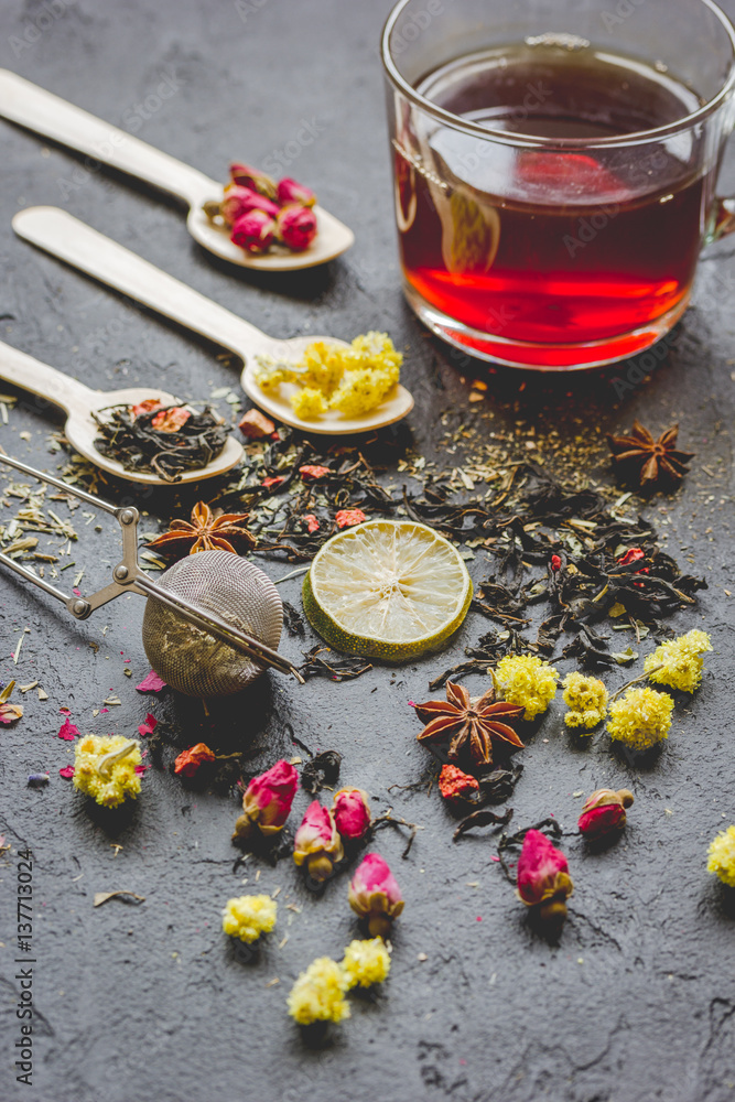 Teacup and herbs on dark stone background