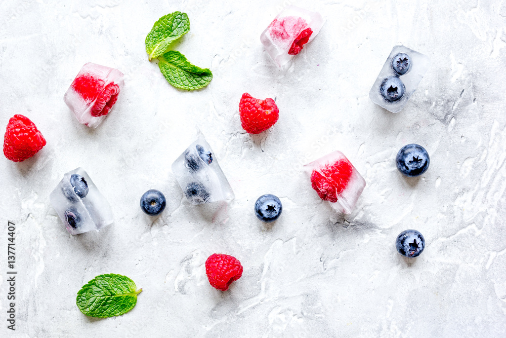 frozen berries in cubes on stone background top view