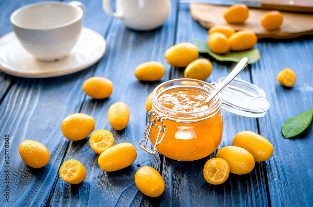 kumquat on plate and jam in jar at wooden table