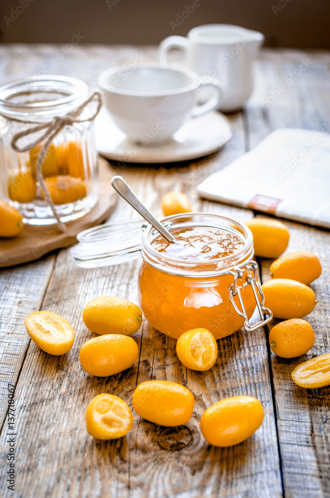 kumquat on plate and jam in jar at wooden table