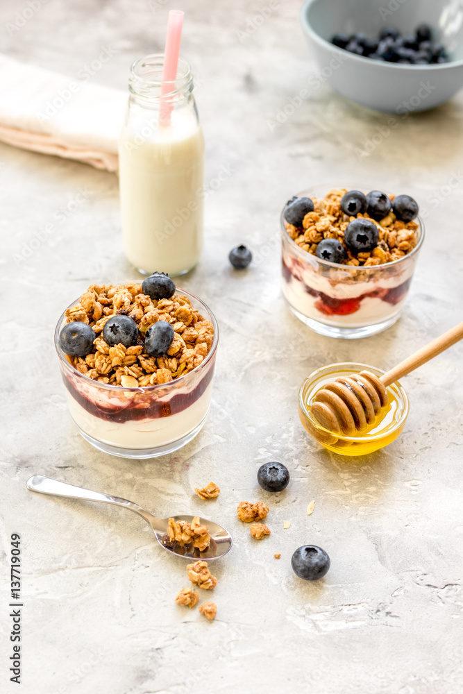 Morning granola in glass with yogurt, honey and milk on white desk